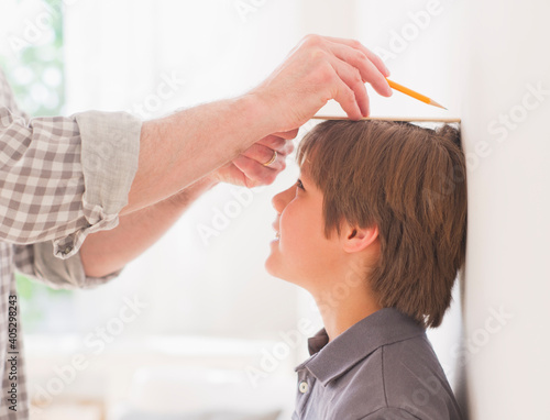 Father measuring son's (10-11 years) height photo