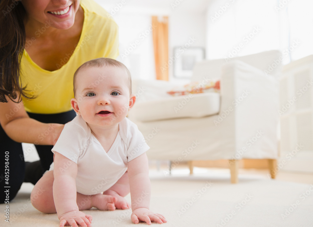 Mother and baby daughter (6-11 months) crawling on carpet Mother and baby daughter (6-11 months) crawling on carpet