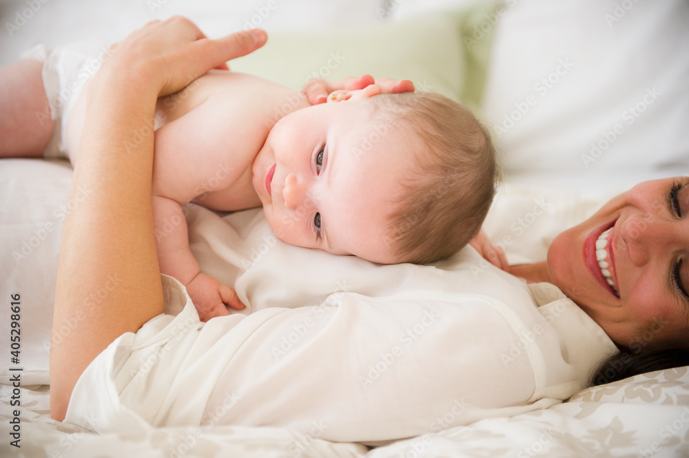 Mother with baby daughter (6-11 months) lying on bed Mother with baby daughter (6-11 months) lying on bed