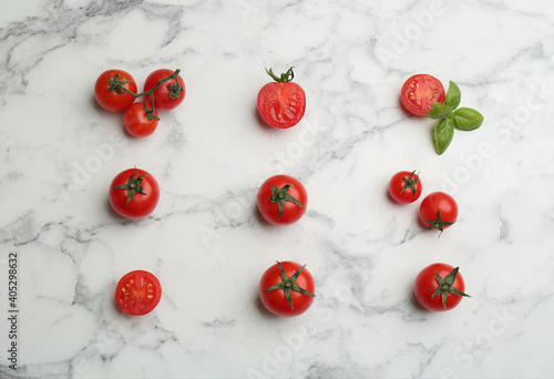 Flat lay composition with fresh cherry tomatoes and basil leaves on white marble table