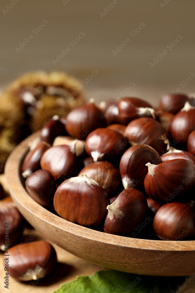 Fresh sweet edible chestnuts in wooden bowl on table, closeup Fresh sweet edible chestnuts in wooden bowl on table, closeup