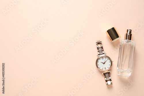 Luxury wrist watch and perfume on beige background, flat lay. Space for text