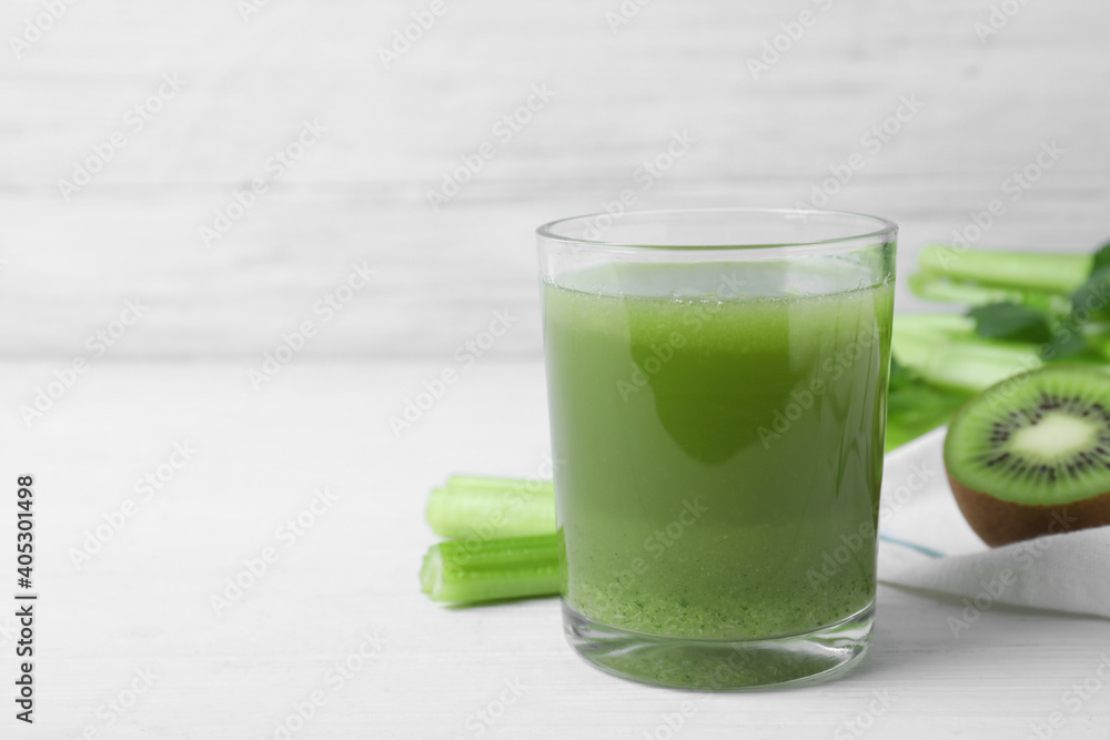 Glass of fresh celery juice on white wooden table, space for text Glass of fresh celery juice on white wooden table, space for text