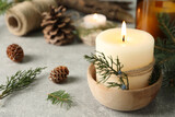 Burning candle with pinecone scent on light grey table, space for text