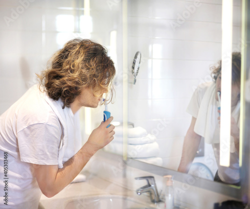 young man looking in the mirror,applying facial cream in bathroom while looking at mirror...