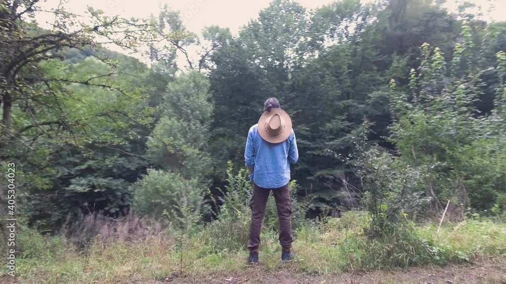 A lonely and sad man alone stands in the forest and looks at the trees. Traveling and hiking cinematic footage. A lonely and sad man alone stands in the forest and looks at the trees. Traveling and hiking cinematic footage.