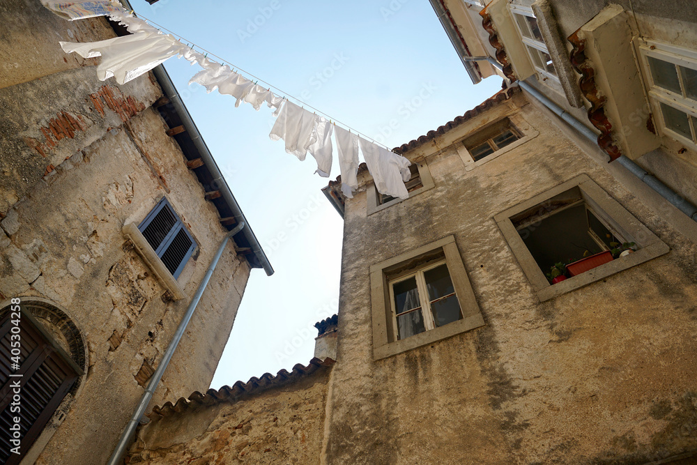 Weiße Wäsche auf einer Wäscheleine in mediterranem Innenhof unter blauem Himmel