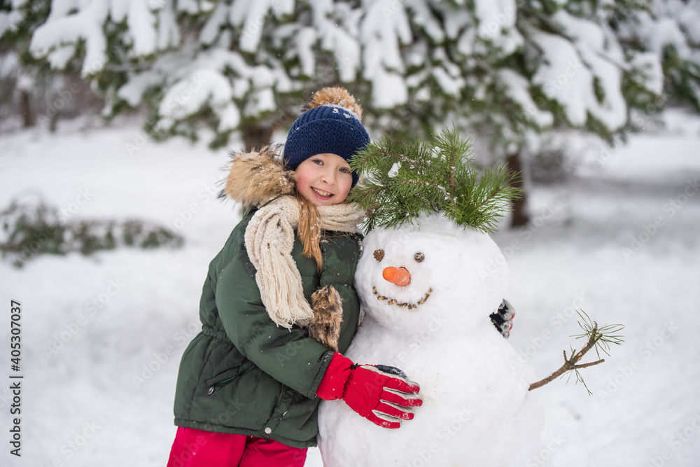 Happy child girl plaing with a snowman on a snowy winter walk Happy child girl plaing with a snowman on a snowy winter walk