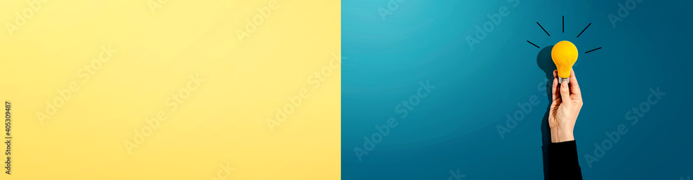 Person holding a yellow light bulb - Idea and creativity theme Person holding a yellow light bulb - Idea and creativity theme