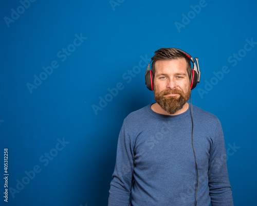 Young man over isolated blue wall listening to music with headphones