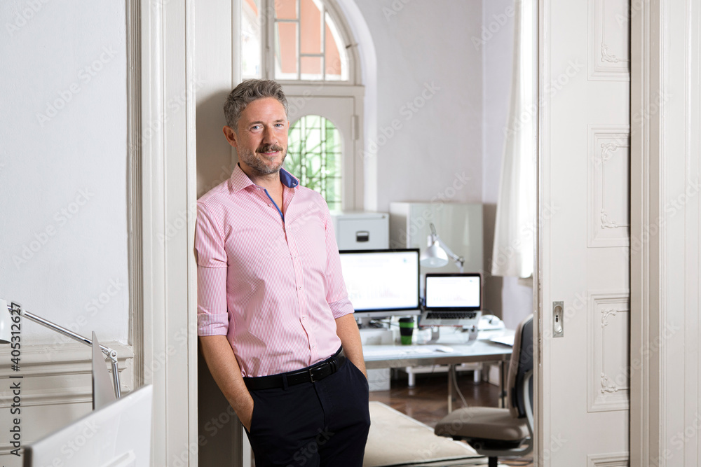 Elegant businessman leaning on doorway of office cabin Elegant businessman leaning on doorway of office cabin
