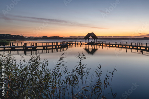 Germany, Schleswig-Holstein, Hemmelsdorf, Silhouette of empty pier on shore of¬†Hemmelsdorfer¬†See lake at dawn photo