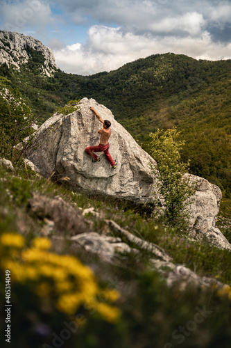 Boulderer climbing rock in mountain landscape