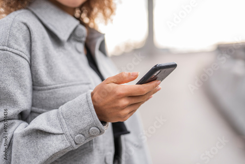 Young woman using smart phone while standing on bridge in city