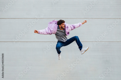 Young man jumping happily against wall photo