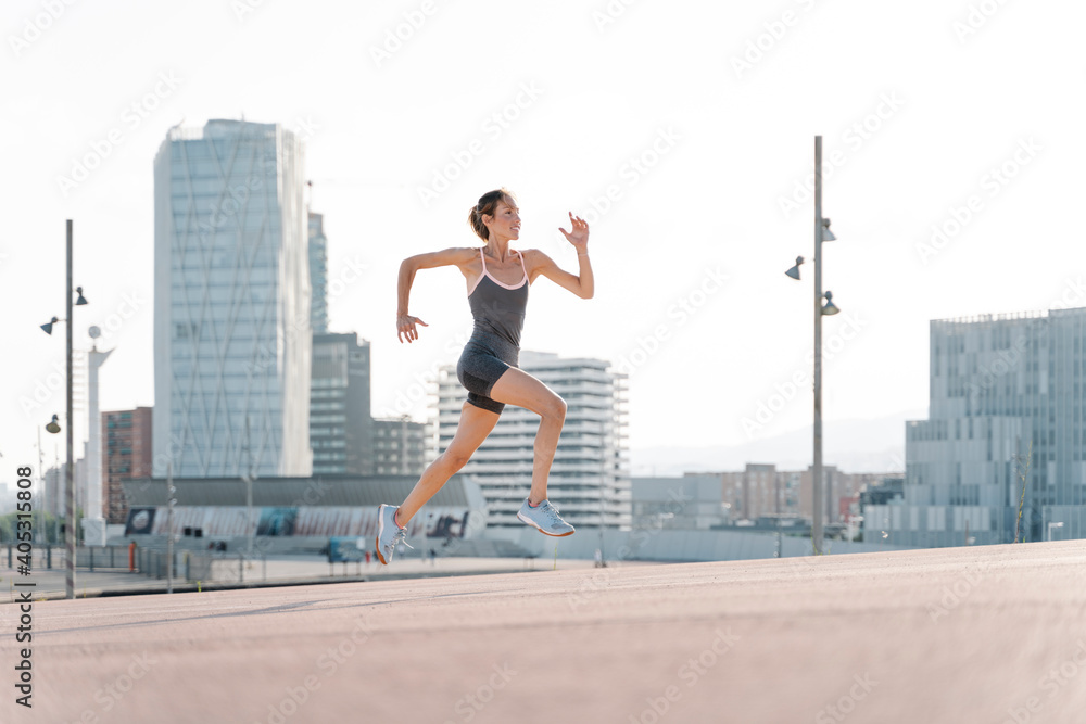 Smiling sportswoman running in in the city Smiling sportswoman running in in the city