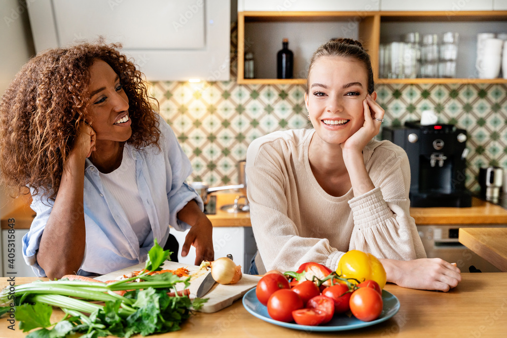 Female colleagues with hand on chin leaning on counter in office kitchen Female colleagues with hand on chin leaning on counter in office kitchen