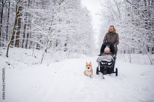 Father and a baby during a walk in winter with a dog