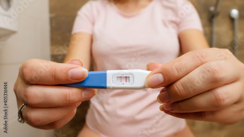 Closeup of woman holding positive pregnancy test and showing it in camera.