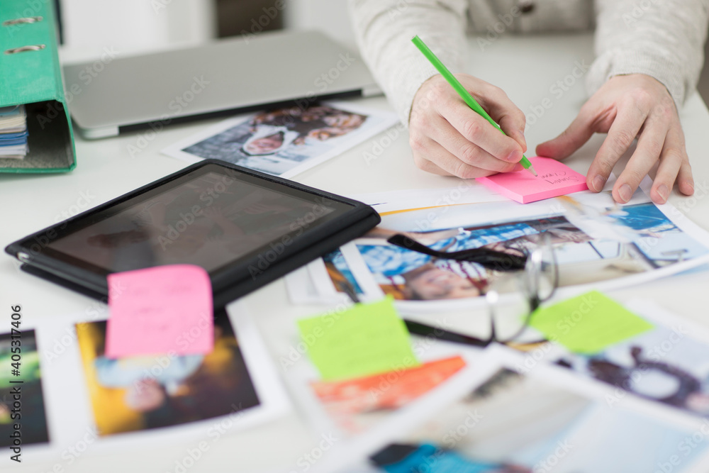 Man making notes on desk with digital tablet and photographs Man making notes on desk with digital tablet and photographs