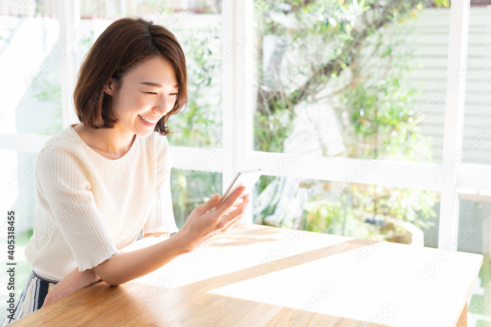 部屋でスマホを見る女性 部屋でスマホを見る女性