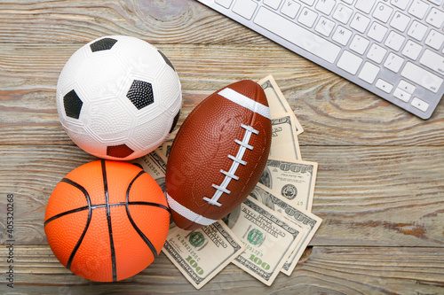 Money  sports balls and keyboard on wooden background