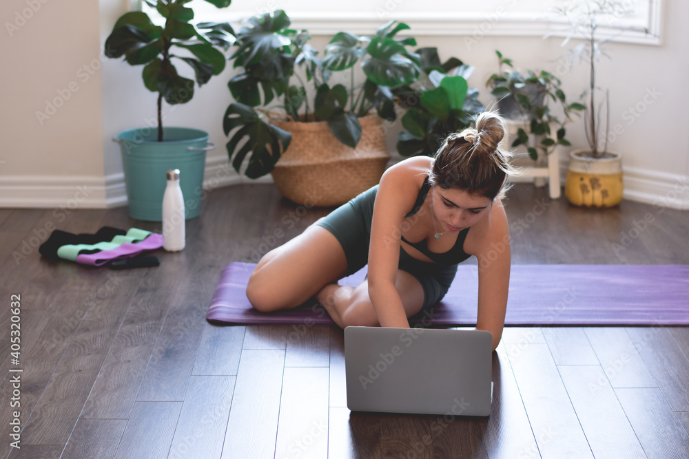 Young woman working out at home using online workout video on laptop computer as a reference Young woman working out at home using online workout video on laptop computer as a reference