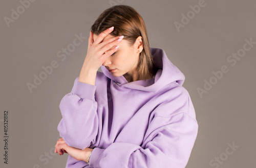 Embarrassed annoyed adult woman hiding face bend head down, facepalm, smirk irritated, not looking friend acting weird, feel humiliated uncomfortable, standing gray background © Яна Солодкая
