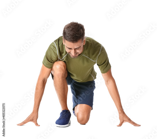 Sporty young man standing in crouch start position isolated on white background. Concept of goal achievement