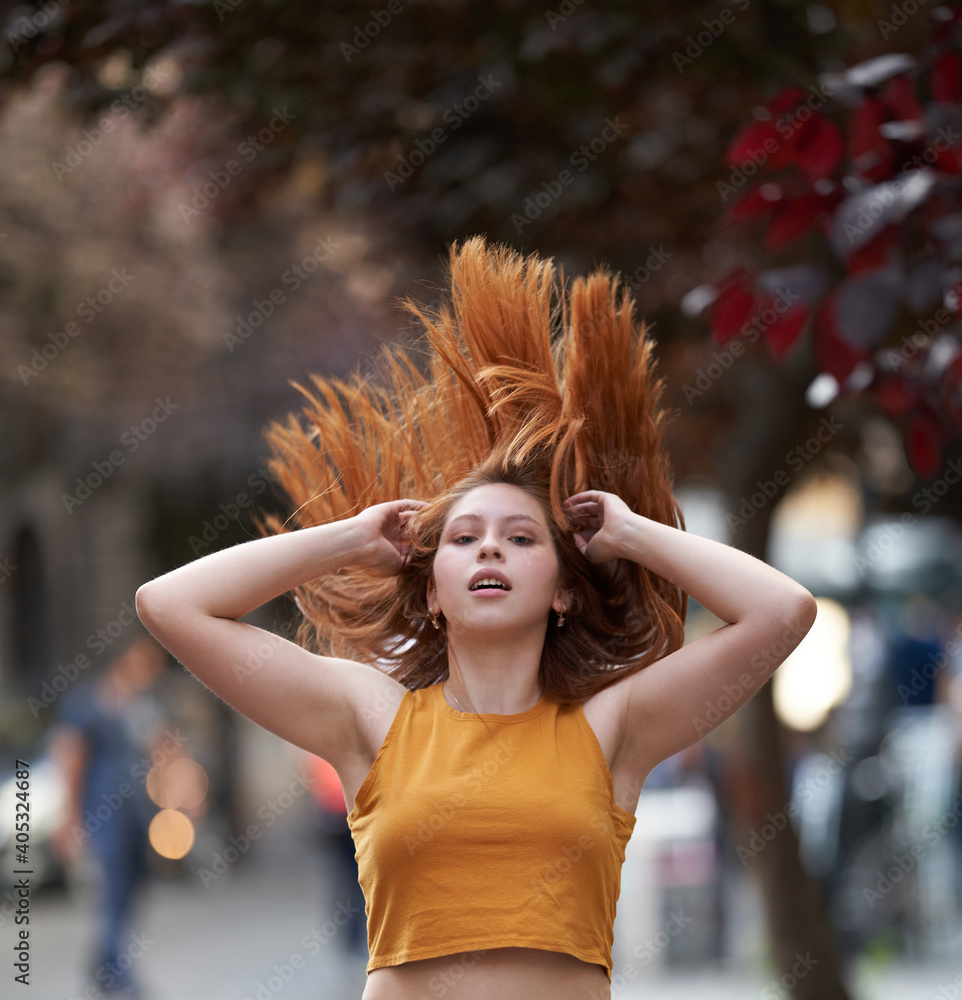 Naklejka premium A beautiful red-haired white Latina woman towards model positions letting the wind blow her hair in an American shot