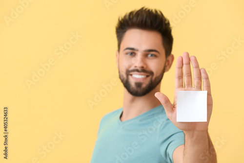 Man with blank note paper on color background