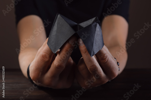 Hands of male fortune teller with paper cootie catcher on dark background photo