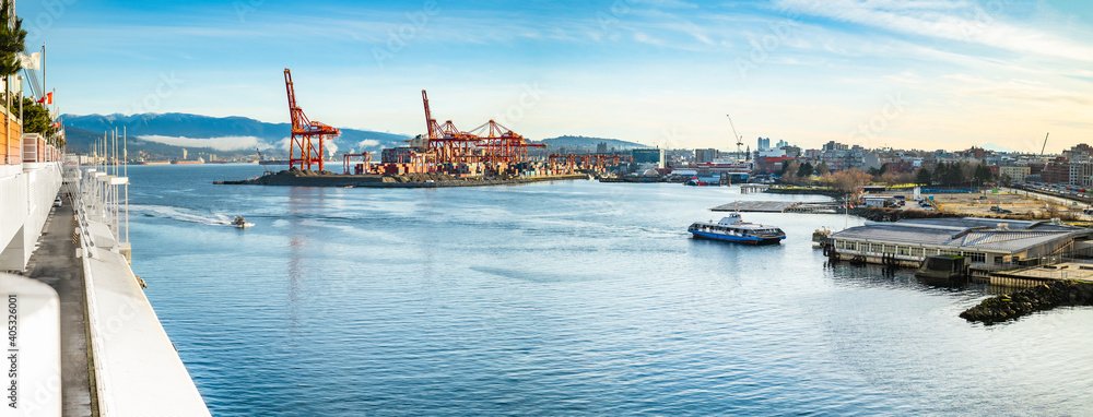 Obraz premium Vancouver Harbour panorama early mornings, on a sunny day. Waterfront city skyline with industry. A seabus ferry is leaving the waterfront station. Industrial cranes with cargo containers and tanker.