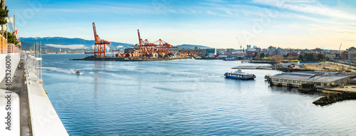 Vancouver Harbour panorama early mornings, on a sunny day. Waterfront city skyline with industry. A seabus ferry is leaving the waterfront station. Industrial cranes with cargo containers and tanker. photo
