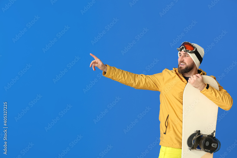 Male snowboarder pointing at something on color background Male snowboarder pointing at something on color background