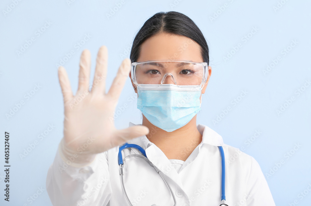 Portrait of female Asian doctor showing STOP gesture on color background Portrait of female Asian doctor showing STOP gesture on color background
