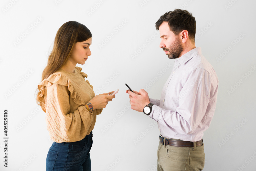 Side view of an hispanic couple texting and flirting Side view of an hispanic couple texting and flirting