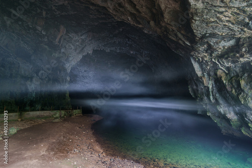 underground river flows out of cave with fog