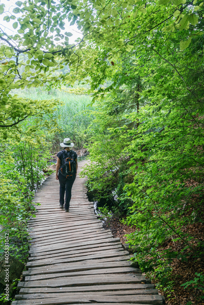 Woman traveler walking on wooden path trail in Plitvice Lakes National Park, UNESCO Woman traveler walking on wooden path trail in Plitvice Lakes National Park, UNESCO