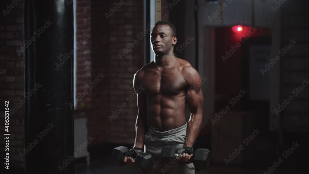 A black man pumping his hands muscles with dumbbells in the gym A black man pumping his hands muscles with dumbbells in the gym