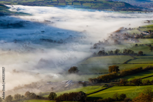 Green fields and rural farmland covered in low hanging mist and fog
