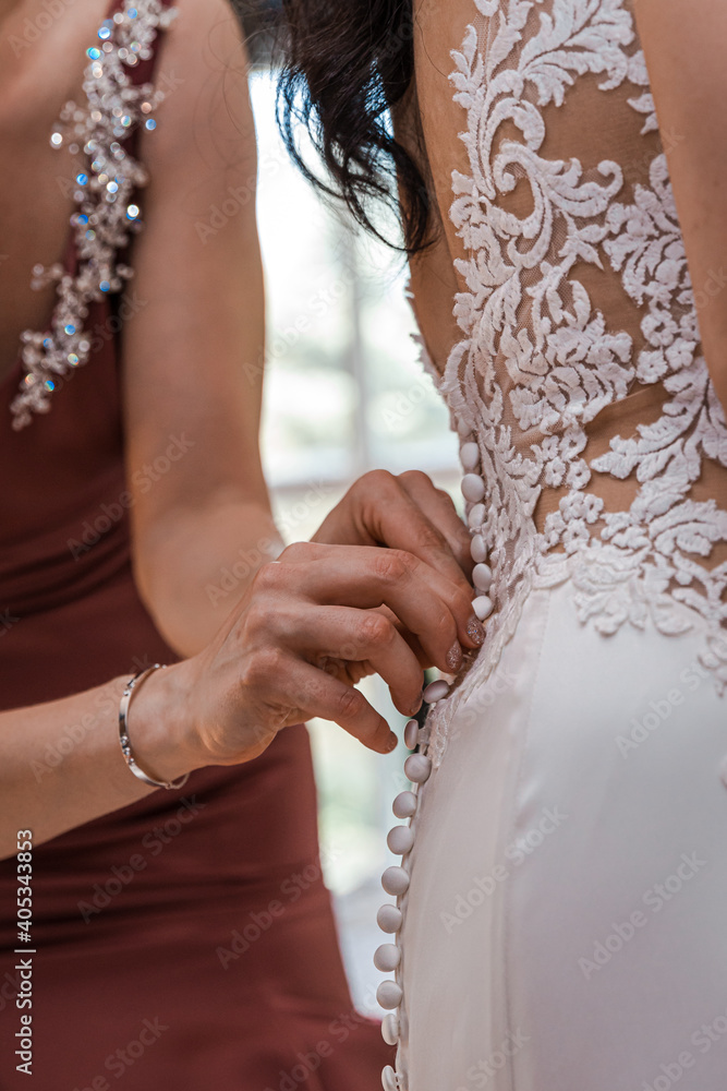 Bridesmaids buttoning up bride's dress
