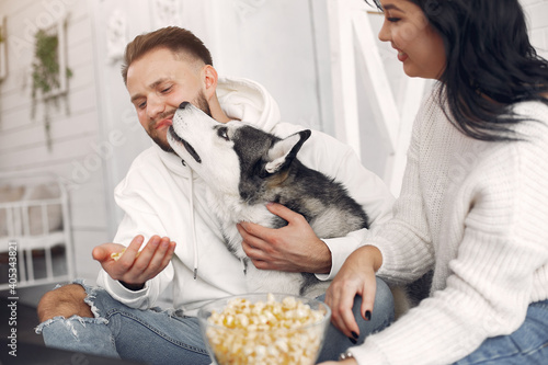 Cute couple in a bedroom. Lady in a white sweater. Pair with a dog