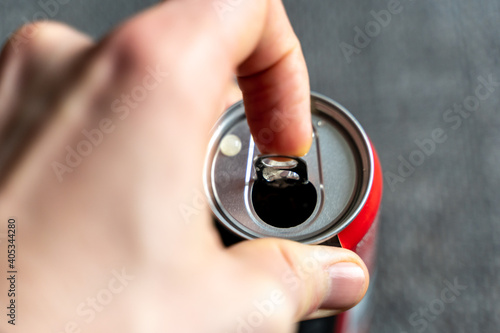 Pulling the tab of a beverage can with a left male hand. Opening a refreshment drink like cola or energydrink after a hard day.