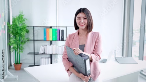 Happy joyful smiling laughing energetic beautiful attractive Asian business woman professional employee worker, in white modern office organizing files, corporate company entrepreneur receptionist.