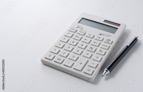 A calculator and pen on a white background © m________k____