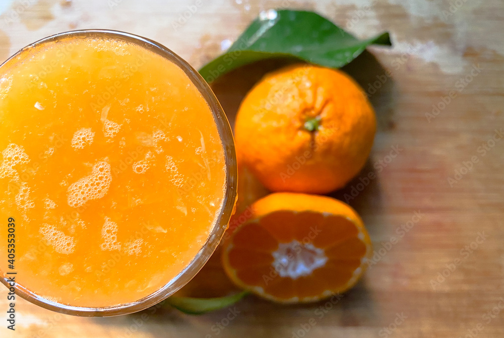 Fresh handmade healthy mandarin juice with two mandarins and a leaf in the background Fresh handmade healthy mandarin juice with two mandarins and a leaf in the background