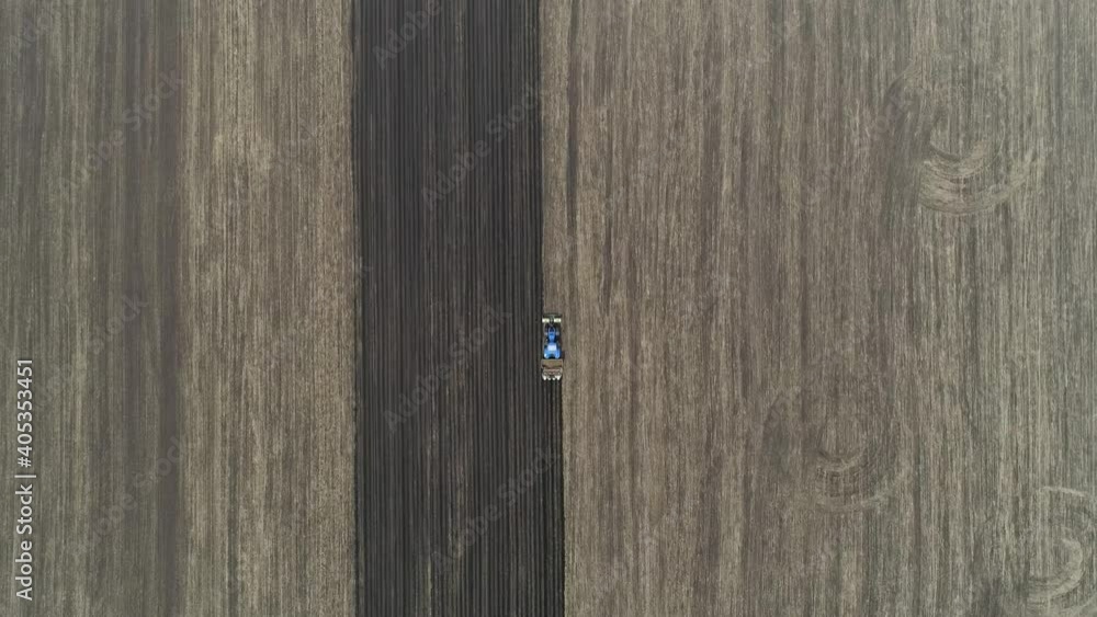 Top down aerial view of a blue tractor with a machine for plant potatoes in the large field of the farm in the spring. The camera goes down
Top down aerial view of a blue tractor with a machine for plant potatoes in the large field of the farm in the spring. The camera goes down