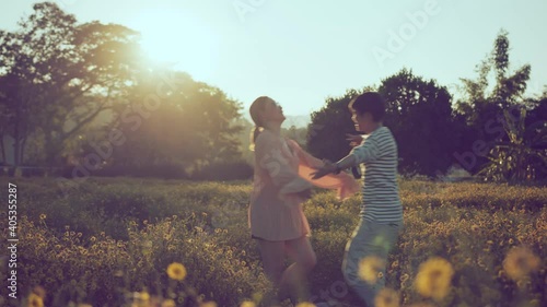 romance mement of the Asian happy romantic couple in love running hold hug together in the flower field at the sunset, hugging and looking at each other. valentine concept photo