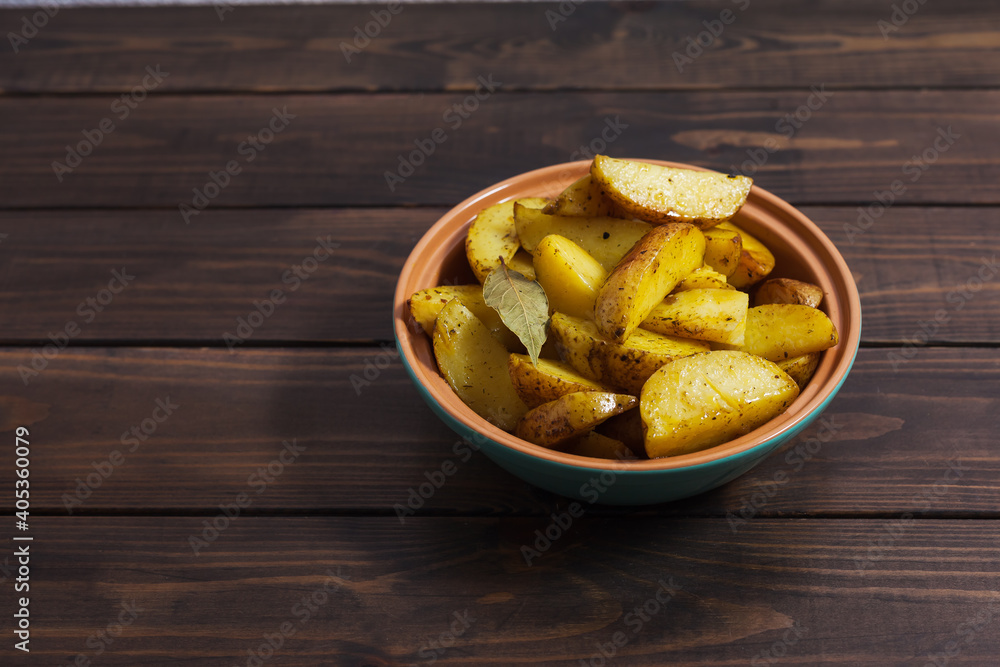 Slices of baked potatoes with herbs in a plate on a wooden table. Horiz. Horizontal orientation, no people, copy space, close-up Slices of baked potatoes with herbs in a plate on a wooden table. Horiz. Horizontal orientation, no people, copy space, close-up